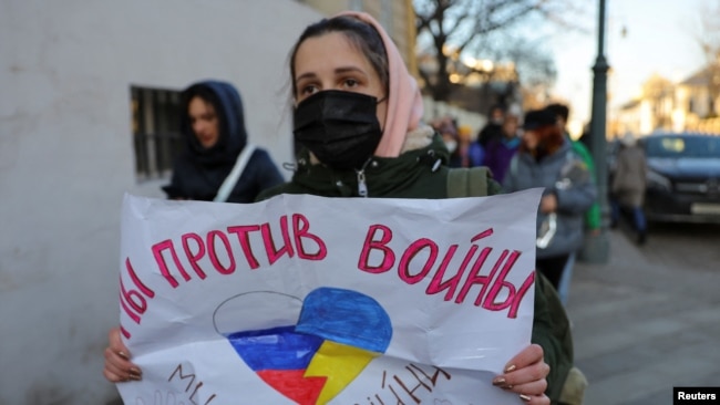 A person holds a sign that reads "We are against war" during a protest against Russian invasion of Ukraine, after President Vladimir Putin authorized a massive military operation, in Moscow, Feb. 27, 2022.
