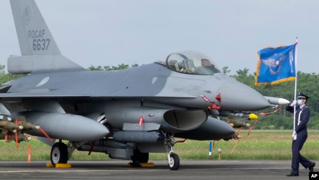 FILE - A Taiwanese Air Force flag bearer passes by an upgraded F-16V fighter jet at the air force base in Chiayi, Taiwan, Nov. 18, 2021.