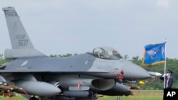 A Taiwanese Air Force flag bearer passes by one of the newly commissioned upgraded F-16V fighter jets at Air Force base in Chiayi in Taiwan, Nov. 18, 2021. 