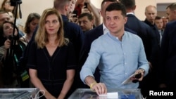 FILE - Ukrainian President Volodymyr Zelenskyy casts his ballot as his wife, Olena, stands nearby at a polling station during a parliamentary election in Kyiv on July 21, 2019.