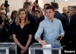 FILE - Ukraine's President Volodymyr Zelenskyy casts his ballot as his wife, Olena, stands nearby at a polling station during a parliamentary election in Kyiv, Ukraine, July 21, 2019.