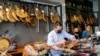 Saleswoman Ainhoa Martinez (R) watches as her chief cuts ham at the Ronda Gourmet shop in downtown Ronda, southern Spain, Sept. 2, 2021.