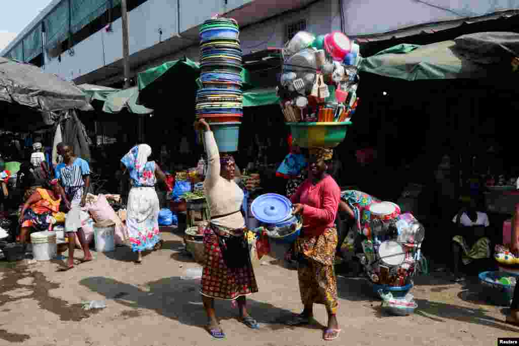 Vendors carry their goods at a market in the popular district of Adjame in Abidjan, Ivory Coast.