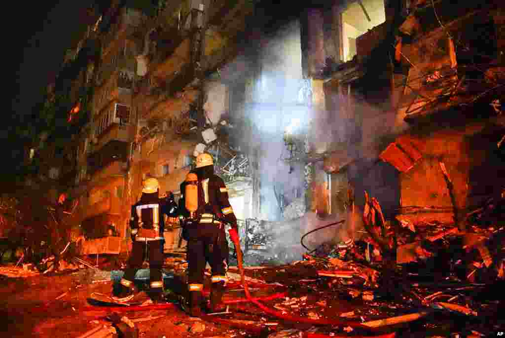 Firefighters examine the damage at a building following a rocket attack on the city of Kyiv, Ukraine, in this image taken from video released by Ukrainian Police Department Press Service.