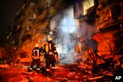 乌克兰国家警察局新闻局公布的照片显示，消防人员检查基辅市一座遭到火箭袭击的建筑。(2022年2月25日)