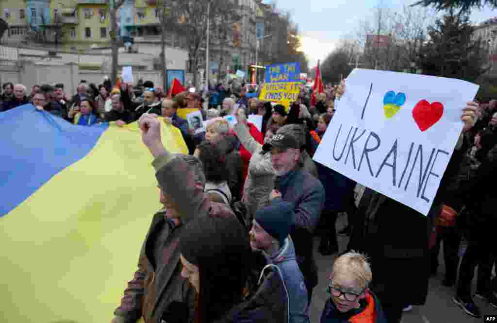 Manifestantes sostienen una enorme bandera ucraniana y pancartas durante una protesta contra la invasión rusa frente a la embajada de Rusia en Tirana, Albania.