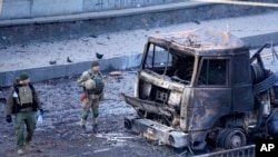 Ushtarët ukrainas duke inspektuar një mjet ushtarak rus të shkatërruar (26 shkurt 2022)