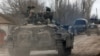 Service members of pro-Russian troops in uniforms without insignia are seen atop of an armored vehicle in the separatist-controlled settlement of Buhas (Bugas), as Russia's invasion of Ukraine continues, in the Donetsk region, Ukraine, March 1, 2022. 