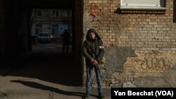 Član građanske milicije čuva stražu ispred zgrade u centru Kijeva, 25. februara 2022.