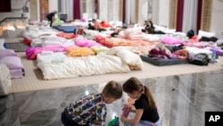 Children who fled the conflict from neighboring Ukraine play on the floor of an event hall in a hotel offering shelter in Siret, Romania, Feb. 26, 2022.