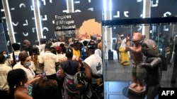 Les visiteurs se tiennent debout pour voir des objets pillés par les soldats coloniaux français retournés et exposés au grand public lors d'une exposition à la présidence à Cotonou, la capitale du Bénin, le 20 février 2022.