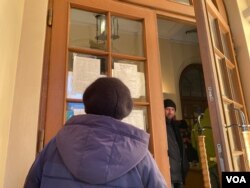 A woman reads a list of volunteers needed to help with emergency needs. (Jamie Dettmer/VOA)