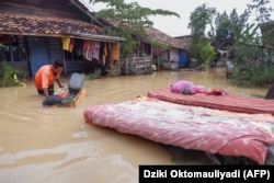 Seorang warga sedang mengeringkan kasurakibat terendam banjir di Desa Sukajaya, Serang pada 2 Maret 2022. (Foto: AFP/Dziki Oktomauliyadi)