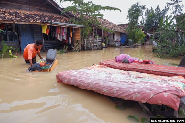 Seorang warga sedang mengeringkan kasurakibat terendam banjir di Desa Sukajaya, Serang pada 2 Maret 2022. (Foto: AFP/Dziki Oktomauliyadi)