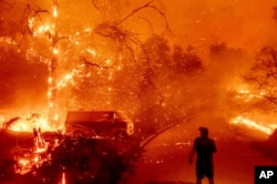 In this file photo, Bruce McDougal watches embers fly over his property as the Bond Fire burns through the Silverado community in Orange County, Calif., on Dec. 3, 2020. (AP Photo/Noah Berger, File)