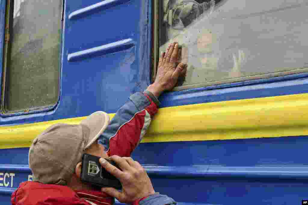 A child speaks on the phone as he says goodbye to a family member looking out the window of a train carriage waiting to leave Kramatorsk for western Ukraine at the railway station in Kramatorsk.