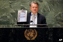 Ukraine's UN Ambassador Sergiy Kyslytsya holds a copy of a screen shot he read from during his address to the emergency session of the United Nations General Assembly, Feb. 28, 2022, in New York.