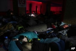 People sleep in the improvised bomb shelter in a sports center, which can accommodate up to 2000 people, in Mariupol, Ukraine, Feb. 27, 2022. (AP Photo/Evgeniy Maloletka)