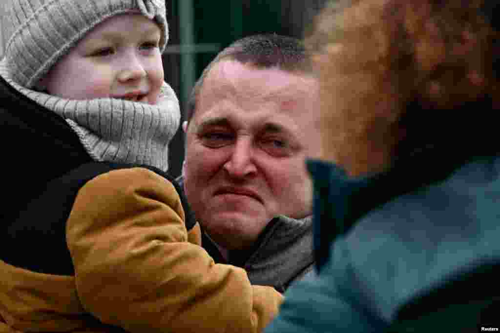 A man from Ukraine reacts as he and a child arrive in Ubla, Slovakia, after Russia launched a massive military operation against Ukraine.