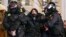 Police officers detain a woman in St. Petersburg, Russia, Feb. 25, 2022. Shocked Russians turned out by the thousands Thursday to protest their country's invasion of Ukraine. Media coverage of the protests has been severely restricted.