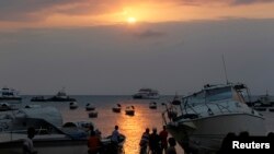 FILE - Residents rest along the beach during sunset near the Port of Zanzibar on the island of Zanzibar July 19, 2012.
