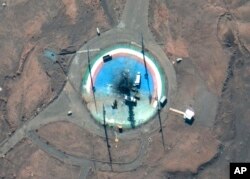 Foto satelit dari Maxar Technologies memperlihatkan truk, dan peralatan lainnya mengelilingi landasan peluncuran yang hangus di Pelabuhan Luar Angkasa Imam Khomeini Iran, 27 Februari 2022. (Foto: via AP)