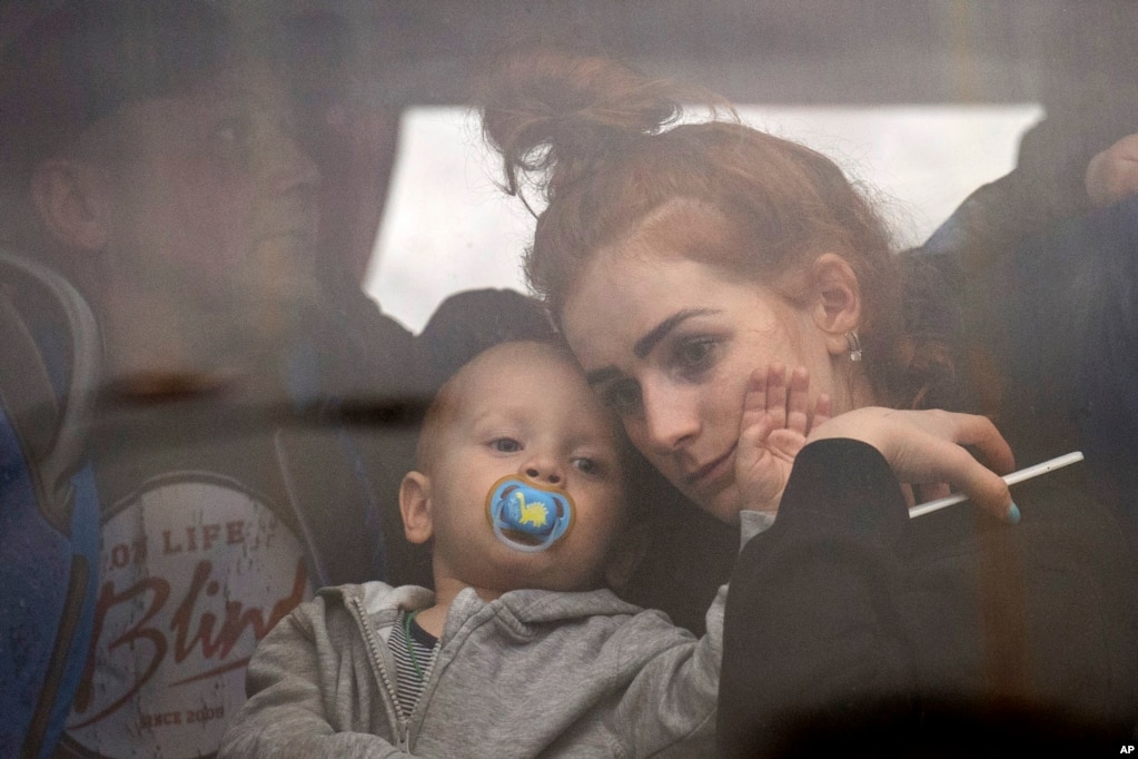 Una mujer sostiene a su bebé dentro de un autobús cuando salen de Kiev, Ucrania, el jueves 24 de febrero de 2022. (Foto AP/Emilio Morenatti)