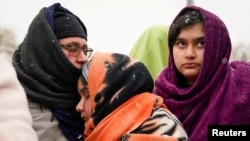 An Afghan family, who once fled the war in Afghanistan, wait to board a bus bound for a refugee center, after fleeing the Russian invasion in Ukraine, in Medyka, Poland, Feb. 28, 2022.