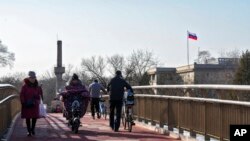 Residents use a bridge near the Russian Embassy in Beijing, Feb. 24, 2022. China repeated calls for talks to resolve the crisis in Ukraine on Thursday while refusing to criticize Russia's attack and accusing the U.S. and its allies of worsening the situation.