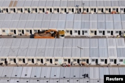 Pembangunan fasilitas isolasi bagi pasien COVID-19 di Tsing Yi di depan tumpukan kontainer kargo di Terminal Kontainer Kwai Tsing, di Hong Kong, 27 Februari 2022. (REUTERS/Tyrone Siu)