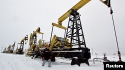 FILE - A worker walks past pump jacks at an oil field east of Izhevsk, Russia, Dec. 7, 2007. 