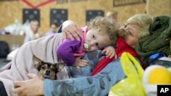 Una mujer sostiene a un niño y a un perro en un refugio dentro de un edificio en Mariúpol, Ucrania, el domingo 27 de febrero de 2022.