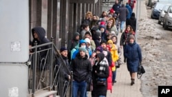 FILE: People stand in line to withdraw U.S. dollars and Euros from an ATM in St. Petersburg, Russia, Feb. 25, 2022.