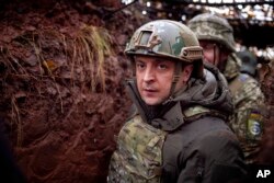 FILE - Ukrainian President Volodymyr Zelenskyy walks under a camouflage net in a trench as he visits the war-hit Donetsk region, eastern Ukraine, Dec. 6, 2021. (Ukrainian Presidential Press Office via AP)