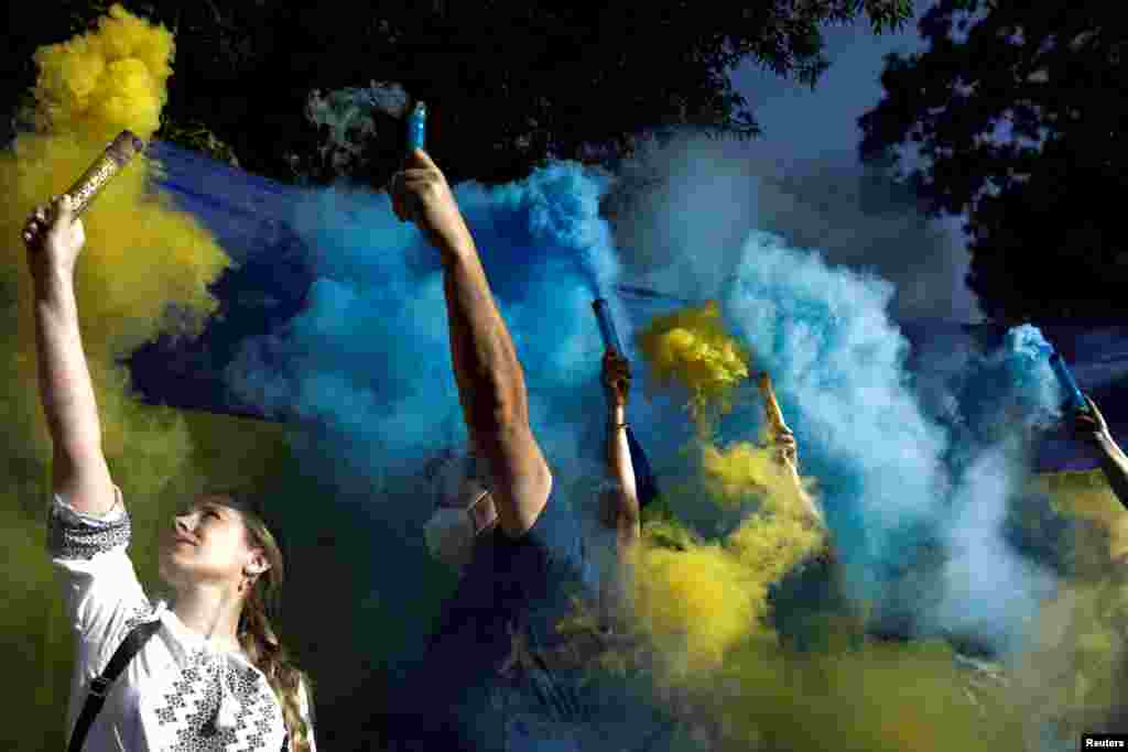 People hold flares with the colors of the Ukrainian flag as Ukrainians and supporters hold an anti-war protest outside the Russian Embassy, following Russia&#39;s invasion of Ukraine, in Mexico City, Mexico, Feb. 28, 2022.