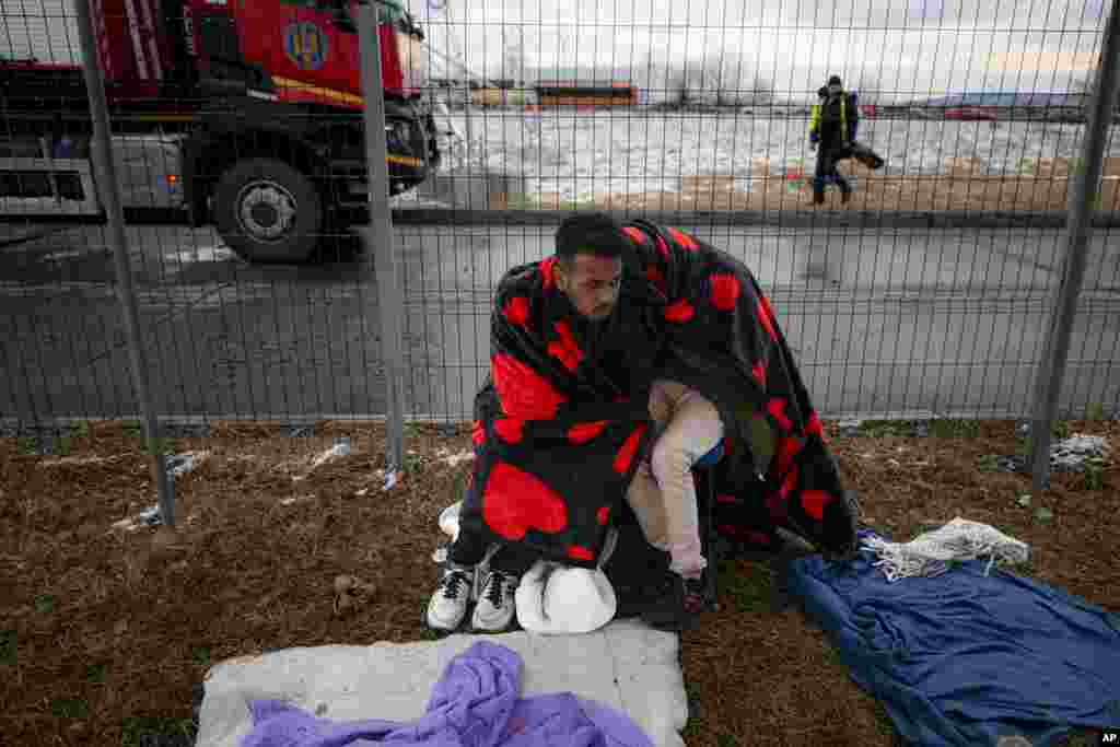 Refugees fleeing the conflict from neighboring Ukraine try to stay warm at the Romanian-Ukrainian border, in Siret, Romania, Feb. 28, 2022.