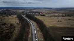 Cars line up on the road to the Shehyni border crossing as people flee to Poland, after Russia launched a massive military operation against Ukraine, outside Mostyska, Ukraine, Feb. 27, 2022.
