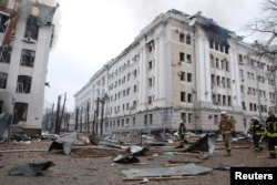 Firefighters work near the buildings of Kharkiv National University and a regional police department, which city officials said were damaged by recent shelling, in Kharkiv, Ukraine, March 2, 2022.