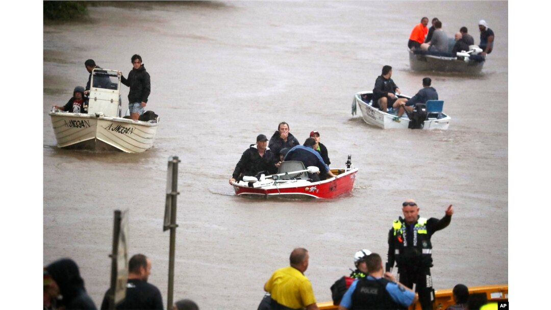 Orang-orang menggunakan perahu kecil untuk melewati jalanan yang terdampak banjir di Lismore, Australia, Senin, 28 Februari 2022. (Jason O'Brien/AAP via AP)