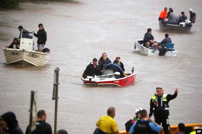 Orang-orang menggunakan perahu kecil untuk melewati jalanan yang terdampak banjir di Lismore, Australia, Senin, 28 Februari 2022. (Jason O'Brien/AAP via AP)