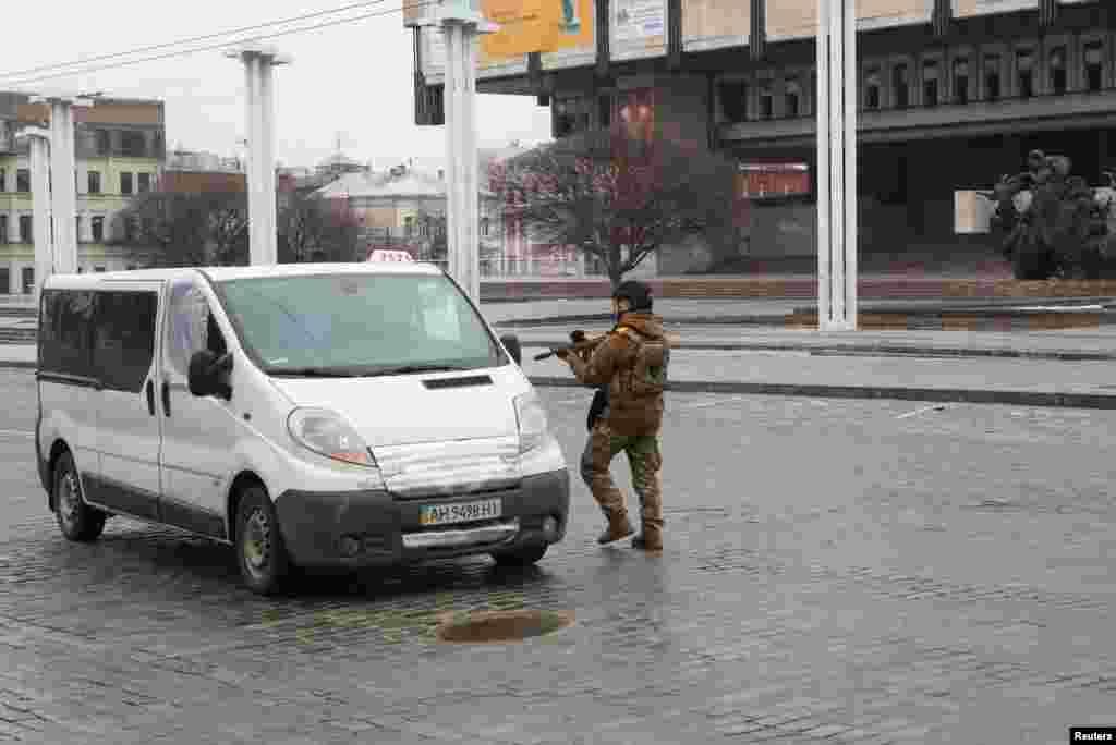 A Ukrainian law enforcement officer holds a weapon while approaching a vehicle in a street in Kharkiv, March 1, 2022.