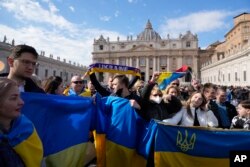 Faithful display Ukrainian flags before the start of Pope Francis' Angelus noon prayer in St.Peter's Square at the Vatican, Feb. 27, 2022.