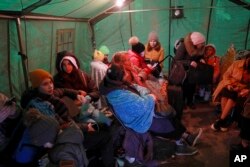 Refugees fleeing the war in Ukraine warm up in a tent after crossing the border in Palanca, Moldova, March 2, 2022.