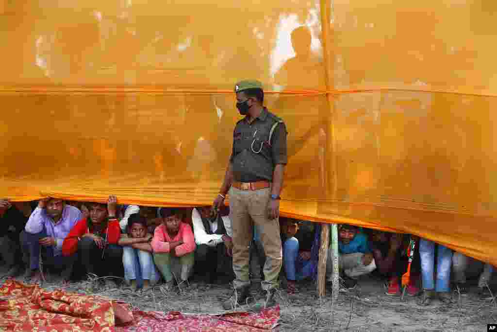 A police officer stands guard as people watch an election rally on the outskirts of Prayagraj, in the northern Indian state of Uttar Pradesh.