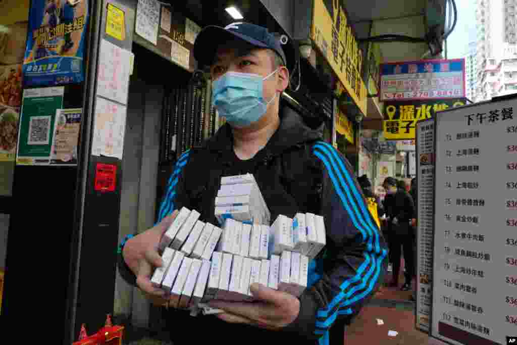 A man wearing face mask carries COVID-19 antigen test kits after purchasing at a market in Hong Kong.