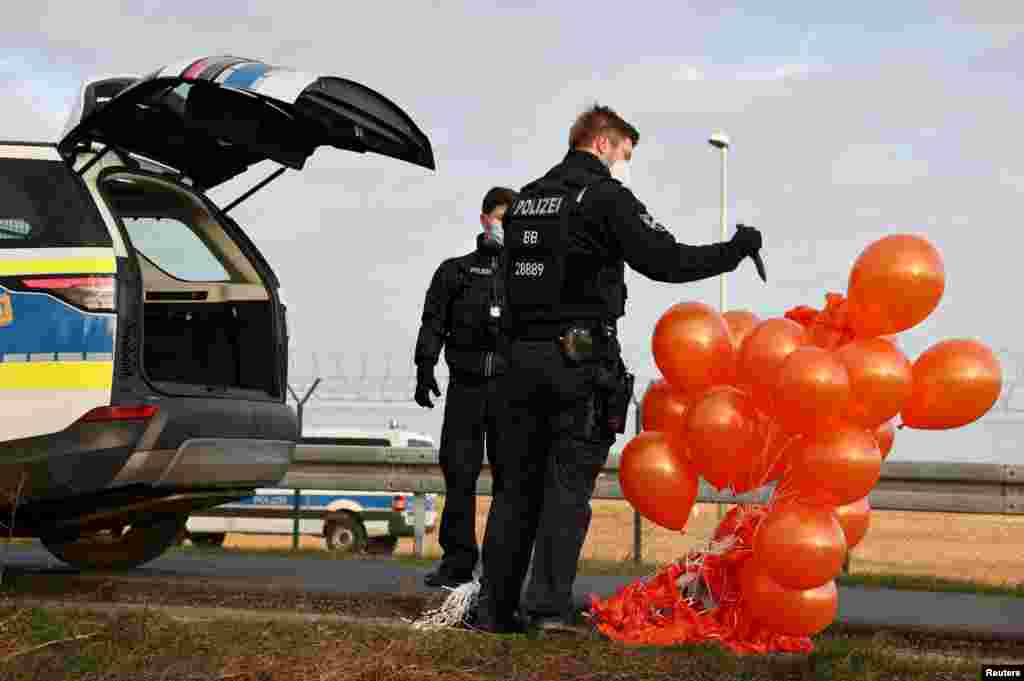 A police officer pops stolen balloons following an activist&#39;s attempt to release balloons to interrupt air traffic at Berlin Brandenburg Airport to protest food waste and greenhouse gas emissions, in Berlin, Germany.