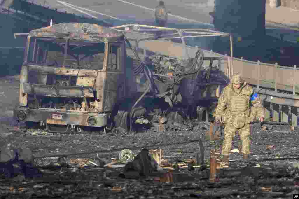 Украински војник поминува покрај остатоците од запален воен камион, на улица во Киев, Украина, 26 февруари 2022 година (АП)