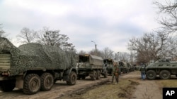 A convoy of military trucks remains parked on a street in Mykolaivka, Donetsk region, territory controlled by pro-Russian militiamen, Feb. 27, 2022, in eastern Ukraine.