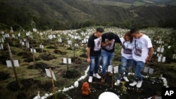 Relatives of Luis Enrique Rodriguez, who died of COVID-19, visit where he was buried on a hill at the El Pajonal de Cogua Natural Reserve, in Cogua, north of Bogota, Colombia, Oct. 25, 2021. 