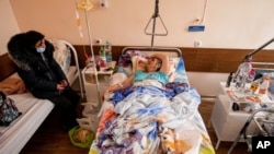 A woman who was wounded during a rocket attack talks with her daughter in a hospital in Mariupol, Ukraine, Feb. 25, 2022.